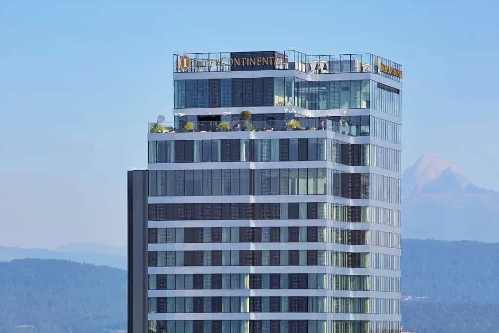 InterContinental hotel skyscraper with rooftop terrace against a backdrop of hazy mountains.
