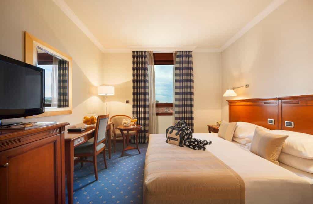 Best Western Premier Hotel Astoria hotel room with wooden furniture, blue carpet, and window view.