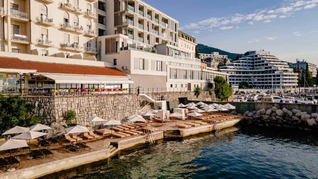 Hotel Istra waterfront sun deck with lounge chairs, umbrellas, and modern buildings overlooking the sea.
