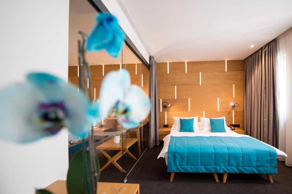 Hotel room with blue bedding, wood paneling, and blurred blue orchid in foreground