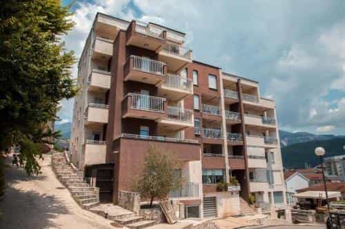 Apartment building with balconies on a steep street near mountains under a cloudy sky
