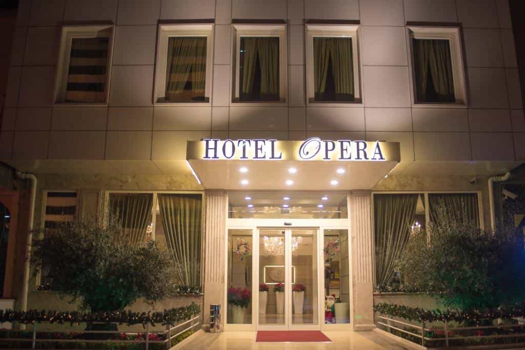 Hotel Opera entrance illuminated at night with olive trees and holiday decorations