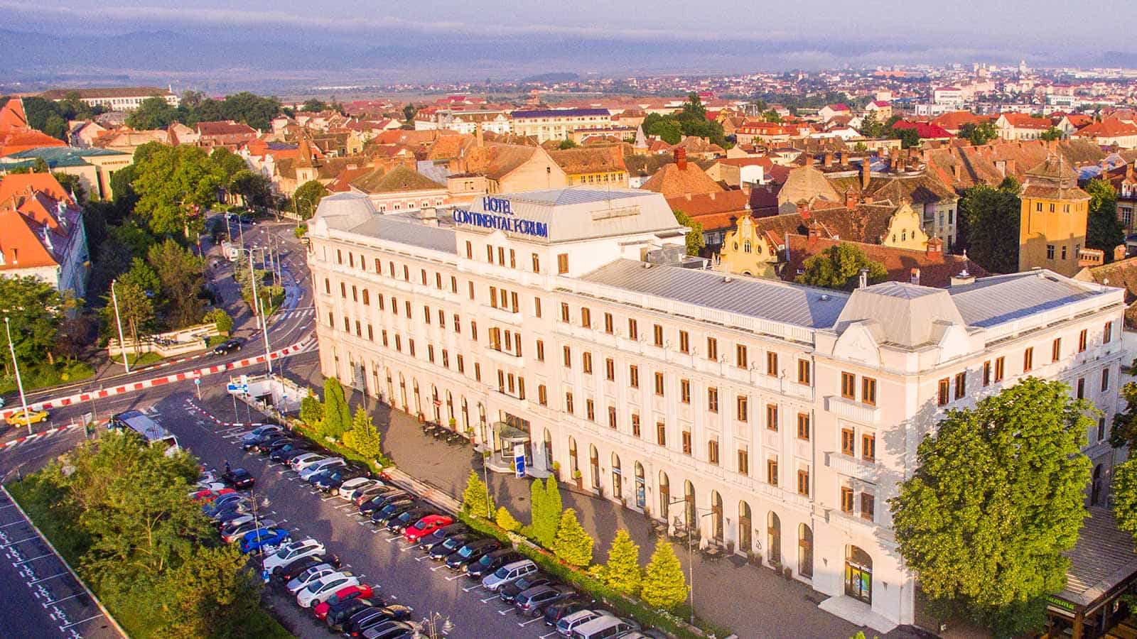 Hotel Continental Forum in Sibiu overlooking historic city center and parking lot.