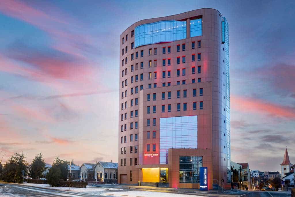 Golden Tulip Ana Tower hotel building at dusk with pink and blue sky and snow on the ground.