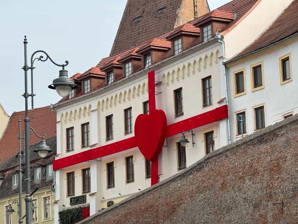 Hotel building facade decorated with a giant red heart and ribbon near a brick wall in Sibu.