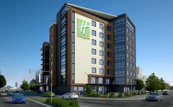 Holiday Inn hotel building exterior on a city street with cars driving by