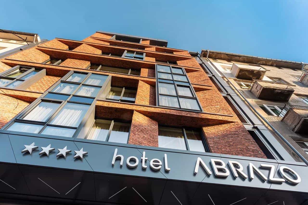 Four-star Hotel Abrazo building facade with modern brickwork and large windows against blue sky.