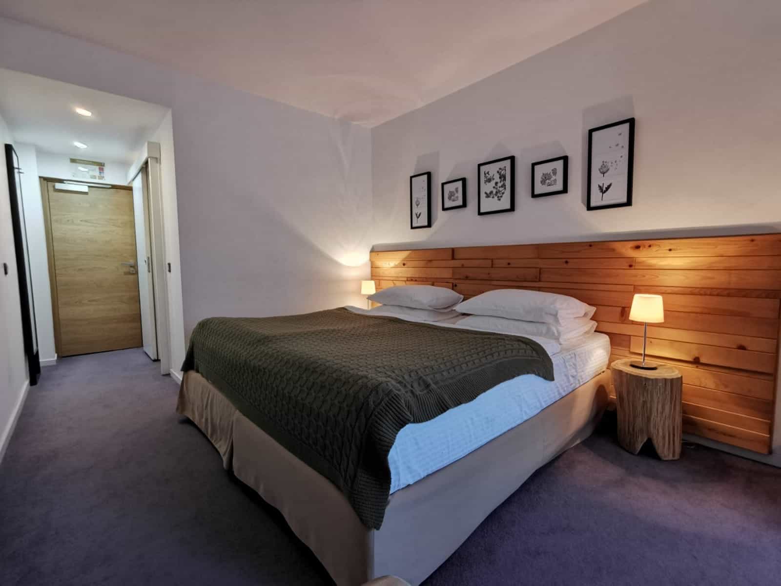 Bedroom with large bed, wooden headboard, and framed botanical prints above.
