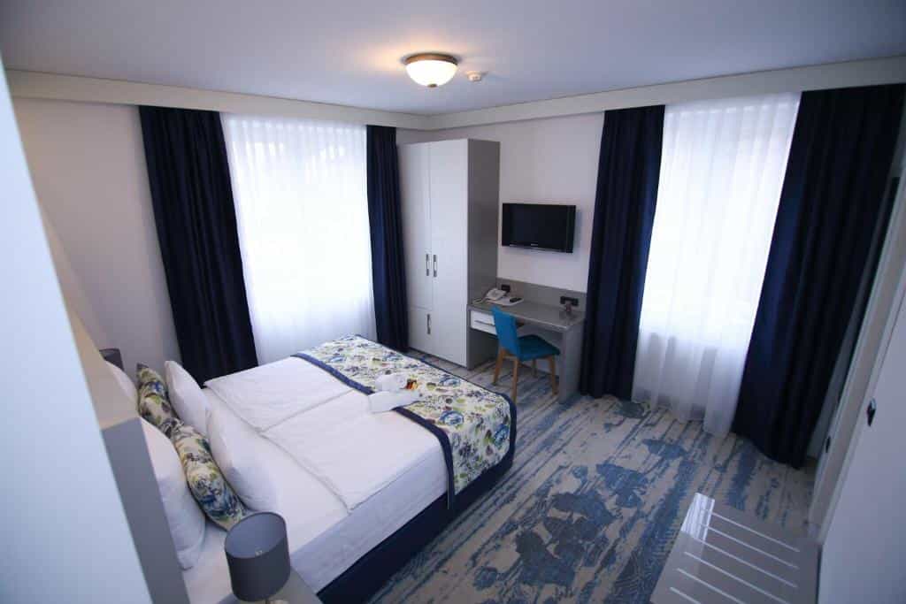 Hotel room with double bed, desk, TV, and blue patterned carpet in Old Town Sarajevo.
