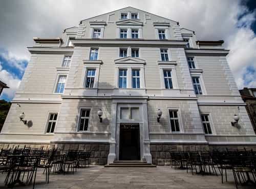 Hotel Central Park Trebinje exterior with stacked chairs on paved terrace under cloudy sky.