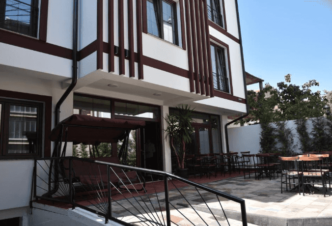 Hotel exterior with white and brown trim, outdoor patio seating, and a porch swing.