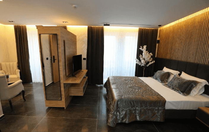 Modern hotel room in Hotel Luna Prizren with dark floors, wood paneling, and a decorative white flowering branch.