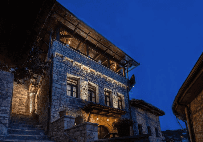 Stone hotel building illuminated at dusk with exterior stairs in Berat, Albania
