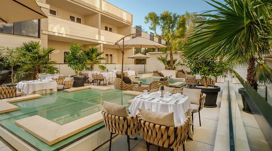 Outdoor dining terrace with white tablecloths, woven chairs, and glass water features at Hotel Palazzo Split.