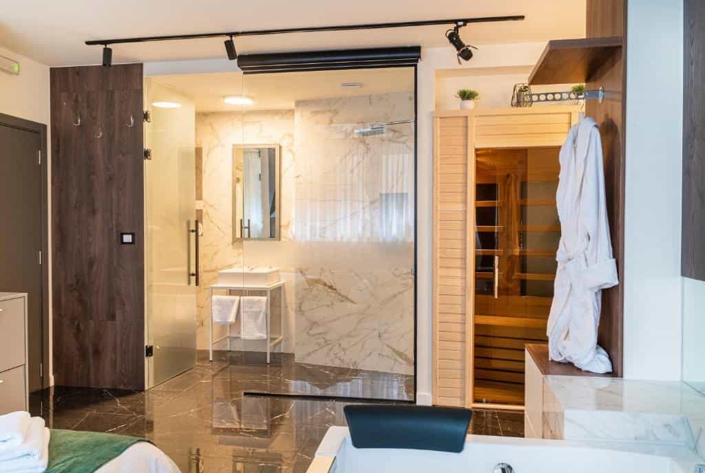Hotel bathroom with marble shower, private sauna, and white bathrobe in Square Nine Hotel Belgrade.