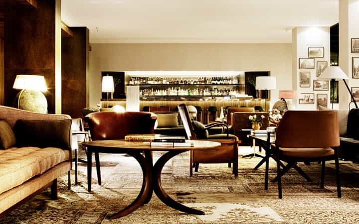 Lobby lounge with leather seating, globe lamp, and illuminated bar area, Square Nine Hotel Belgrade.