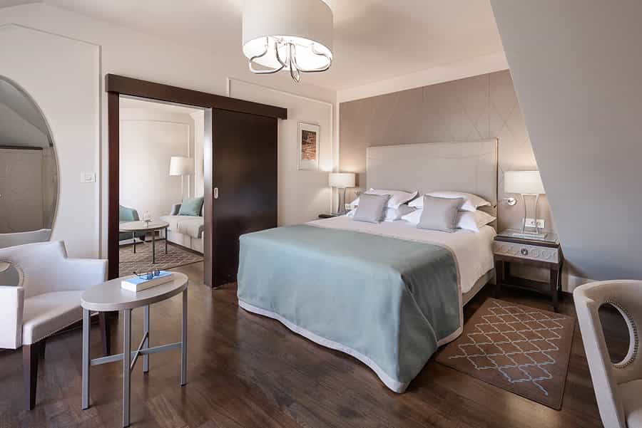 Hotel bedroom with large bed, sitting area, and sliding door to an adjoining room in Zadar.