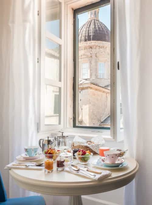 Breakfast table with fruit and tea overlooking Dubrovnik Cathedral dome through window