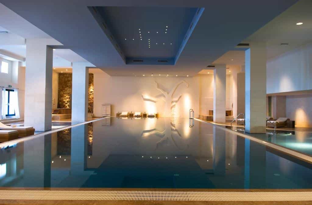 Indoor swimming pool with illuminated tree relief and lounge chairs at Hotel Excelsior Dubrovnik.