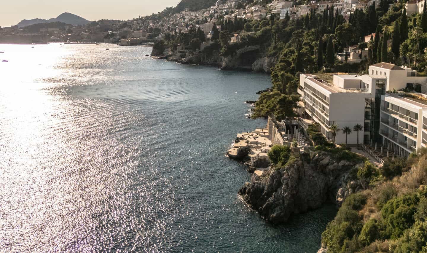 Modern white hotel on rocky Mediterranean coastline overlooking sparkling sea near Dubrovnik.