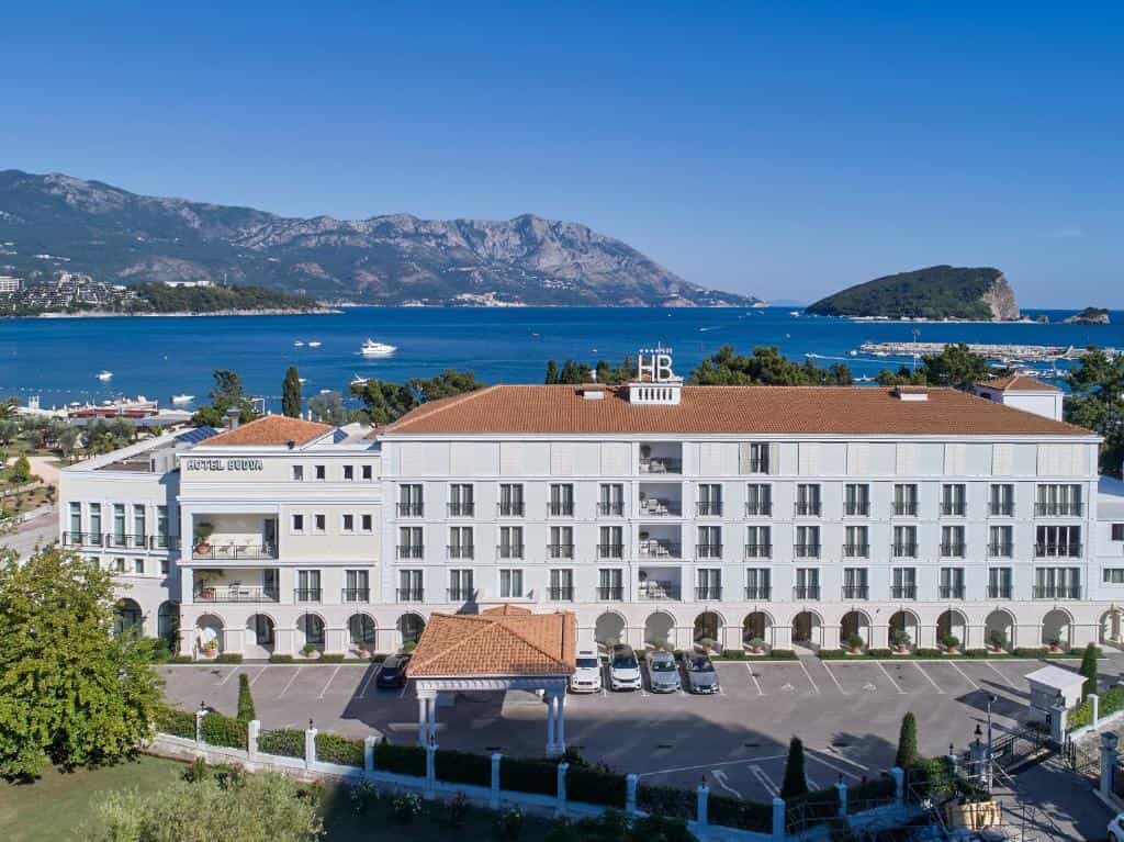 Hotel Budva with parking lot, overlooking the sea, mountains, and Sveti Nikola island.