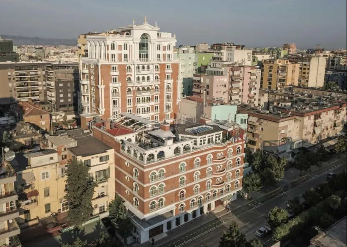 Xheko Imperial Hotel in Tirana surrounded by dense city buildings under a clear sky.