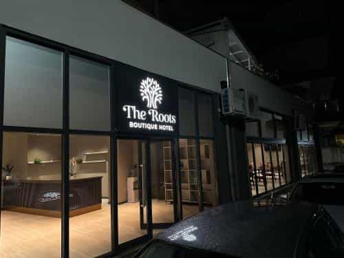 The Roots Boutique Hotel entrance illuminated at night with cars parked outside in Shkoder, Albania.