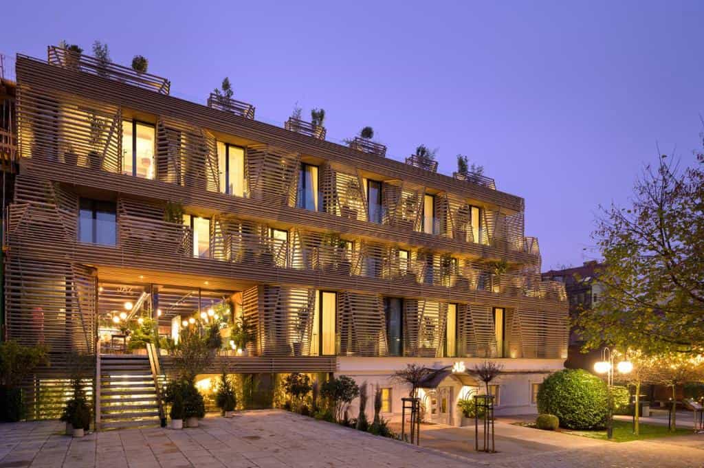 Boutique hotel exterior with modern wooden facade illuminated at dusk in Ljubljana.