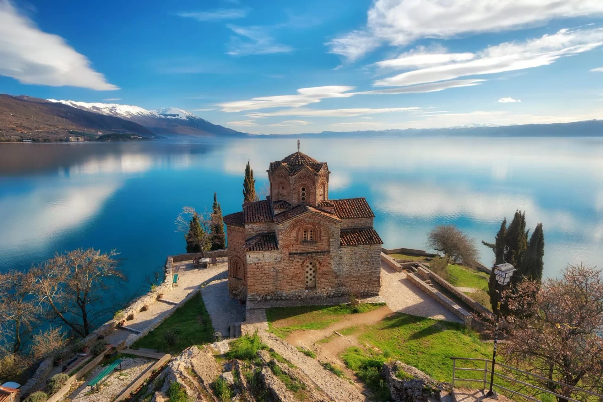 Church of Saint John the Theologian overlooking Lake Ohrid with snow-capped mountains.