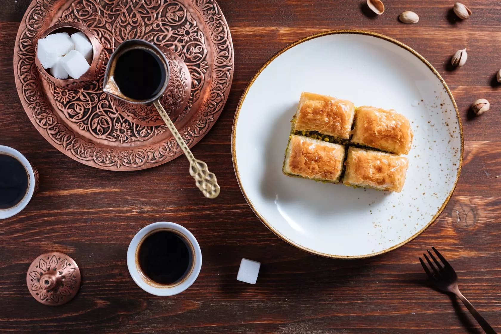 Baklava pastry and Turkish coffee with sugar cubes on dark wood table