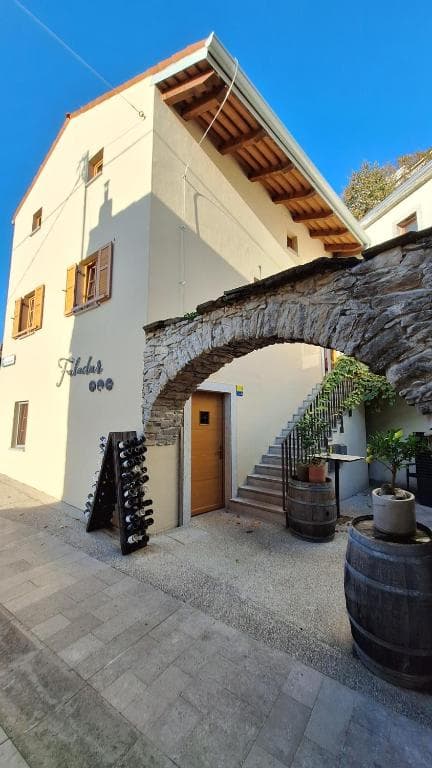Building entrance with stone archway, wine rack, and barrels in Vipava.