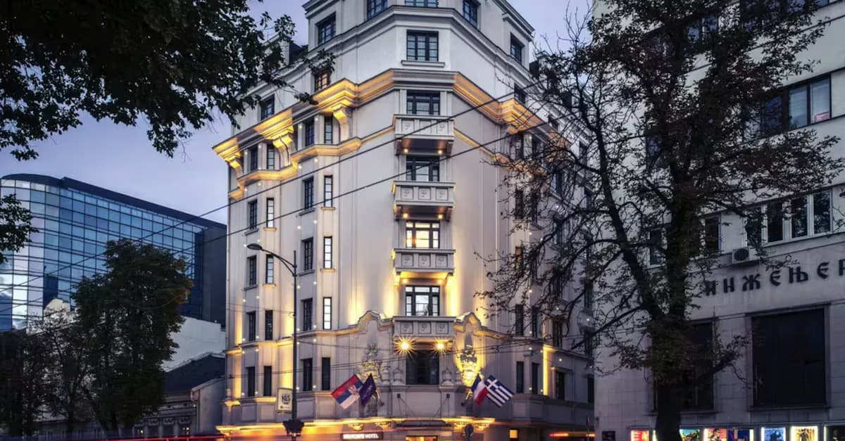 Mercure Excelsior hotel building with illuminated facade and flags in a city square.