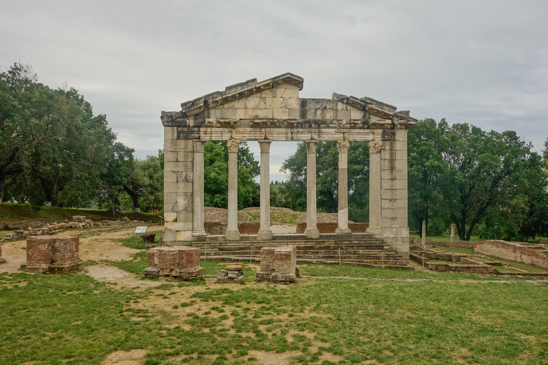 Ruins of a stone structure with columns at Apollonia Archaeological Park under an overcast sky.