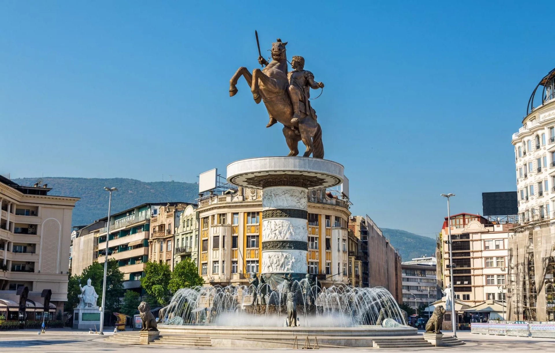 Alexander the Great statue on rearing horse above fountain in Skopje city center with mountains.