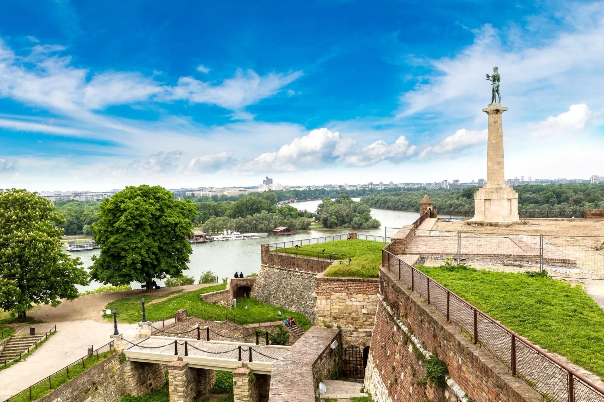 Belgrade Kalemegdan fortress walls, Victor Monument, and confluence of rivers under blue sky.