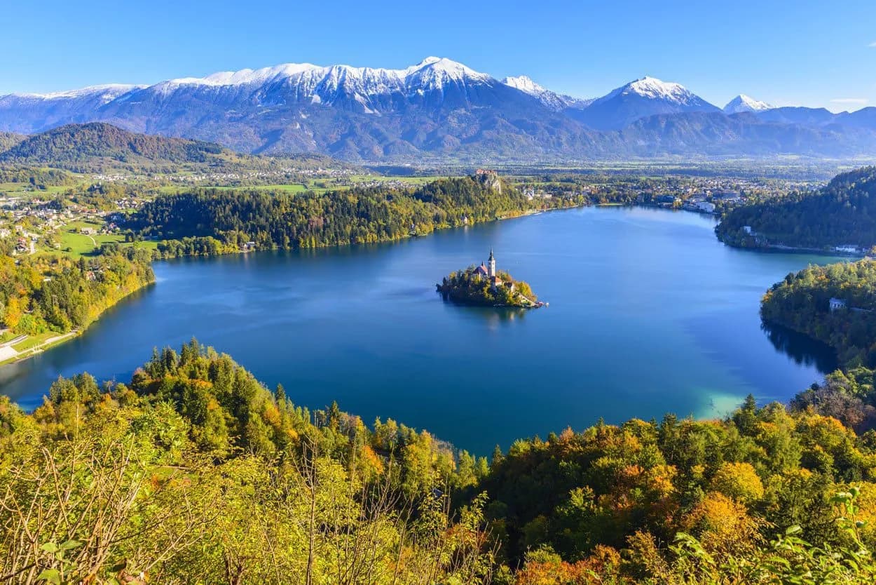 Lake Bled island church with Julian Alps snow-capped mountains in autumn