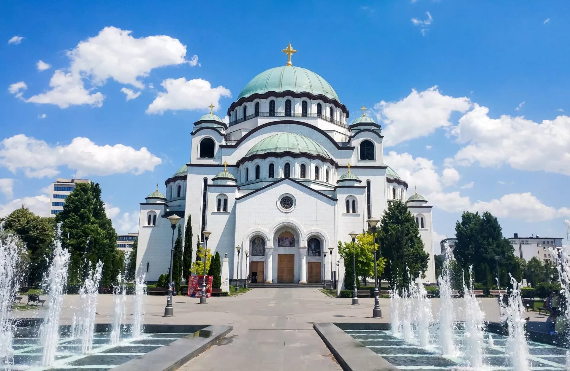 Church of Saint Sava in Belgrade, Serbia, with fountains and blue sky.