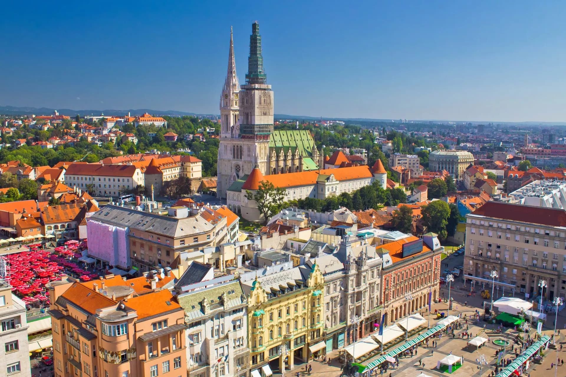 Aerial view of Zagreb Main Square with cathedral towers and dense orange-roofed city buildings.