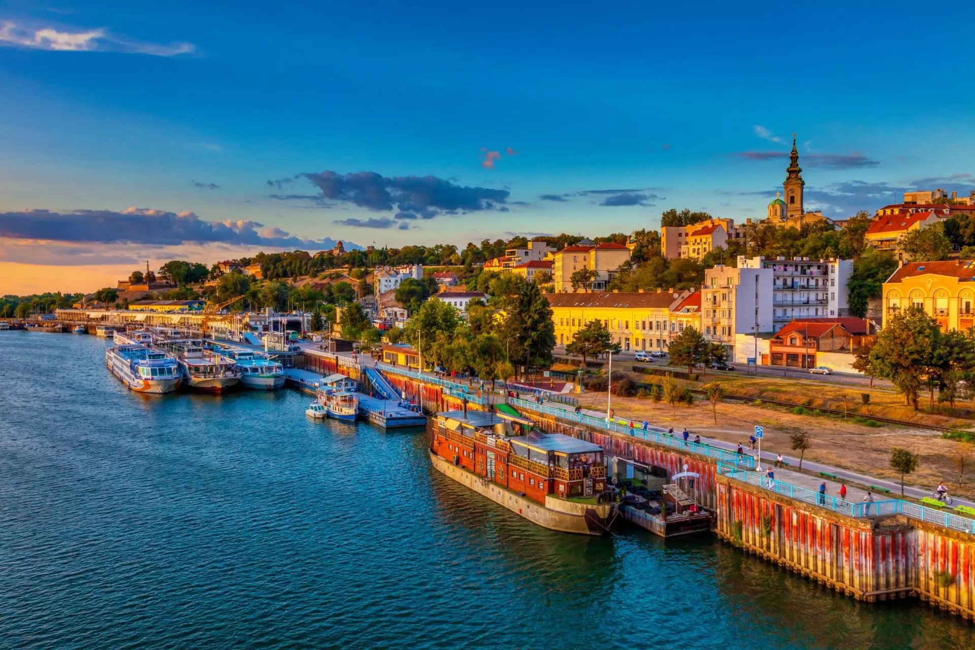 Sunset over Belgrade with ships docked in the harbor along the riverfront.