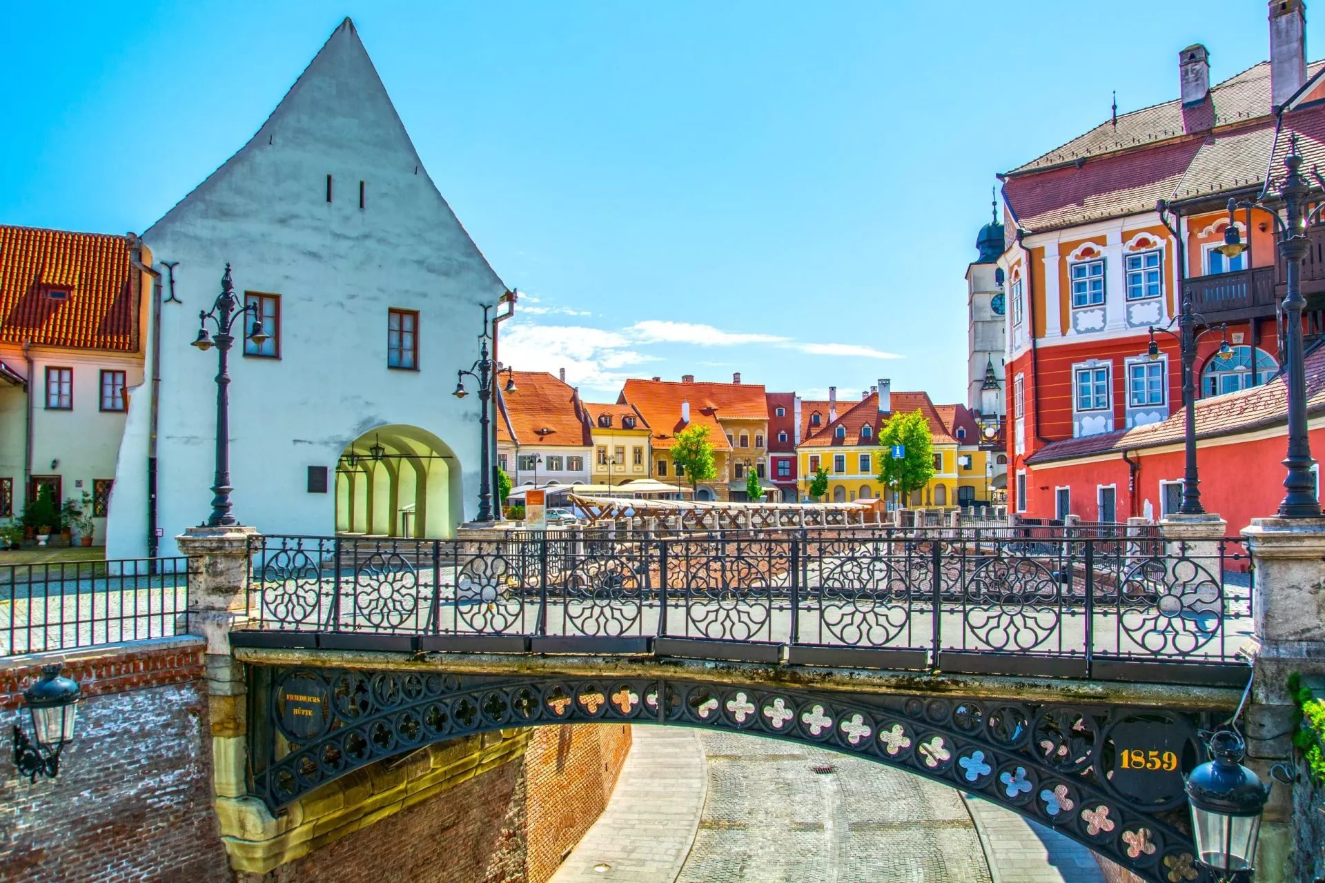 Liars Bridge over dry cobblestone path in Sibiu, Transylvania, Romania, with colorful buildings.