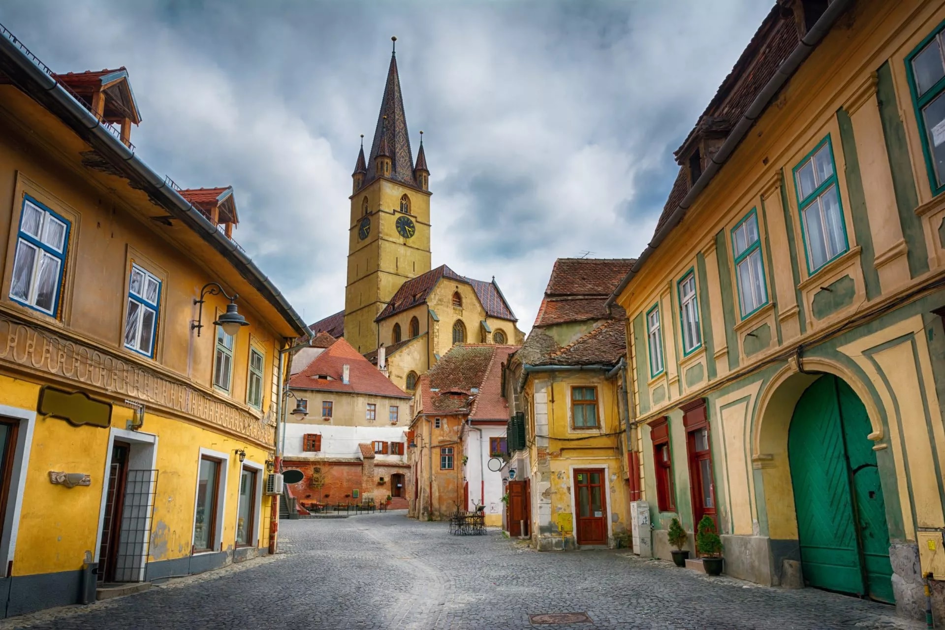 Cobblestone street leading to the tall clock tower of the historical center of Sibiu town.