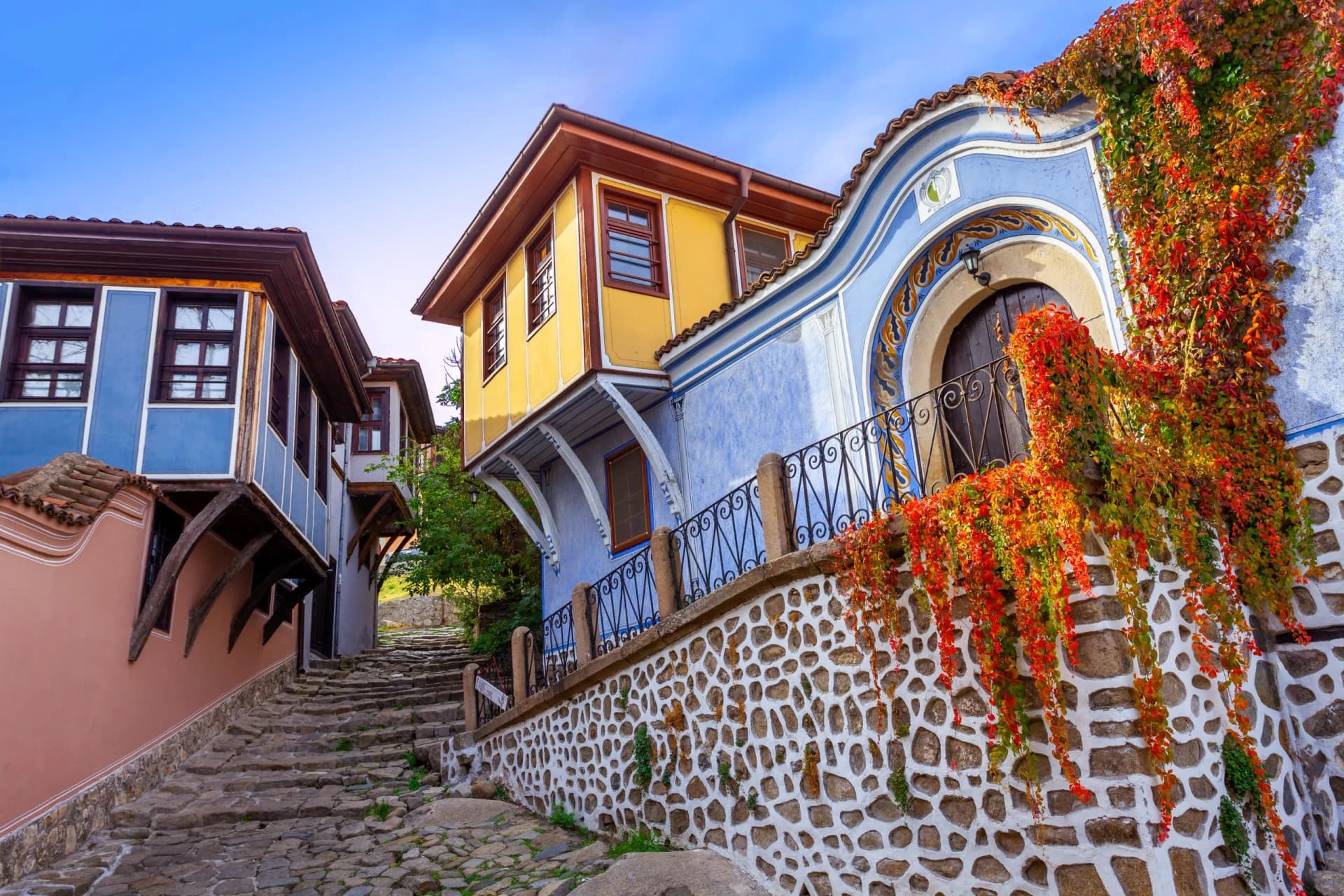 Colorful historic houses line a steep cobblestone street in Plovdiv Old Town, Bulgaria.