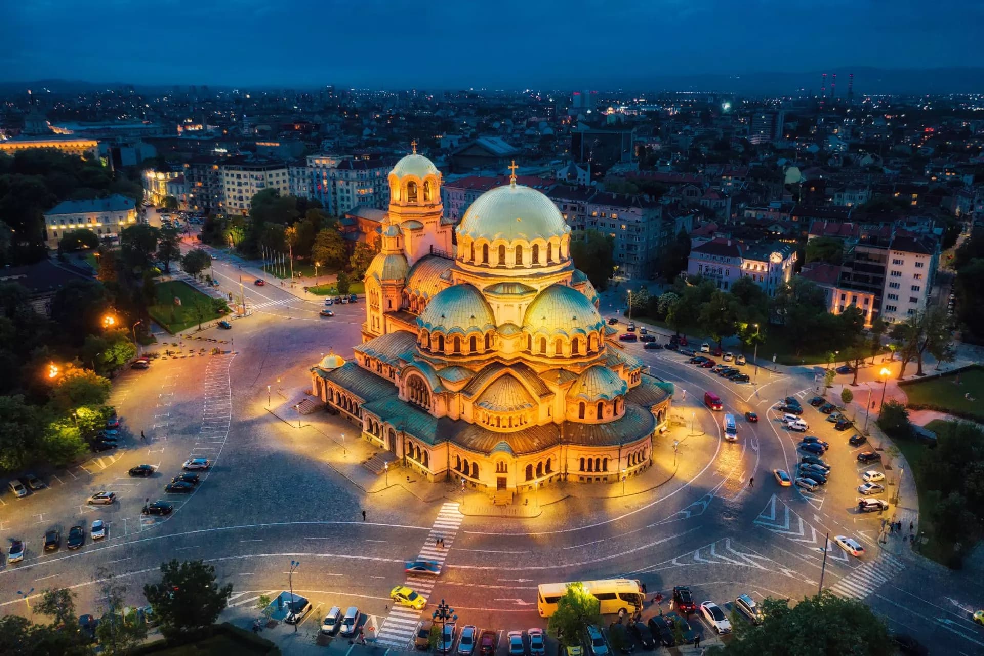 Alexander Nevsky Cathedral illuminated at night in Sofia, Bulgaria, surrounded by city streets.
