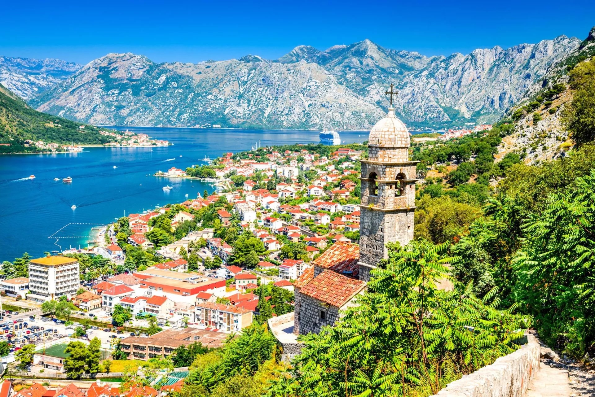 Kotor, Montenegro coastal town with stone bell tower overlooking the Adriatic Sea and mountains.