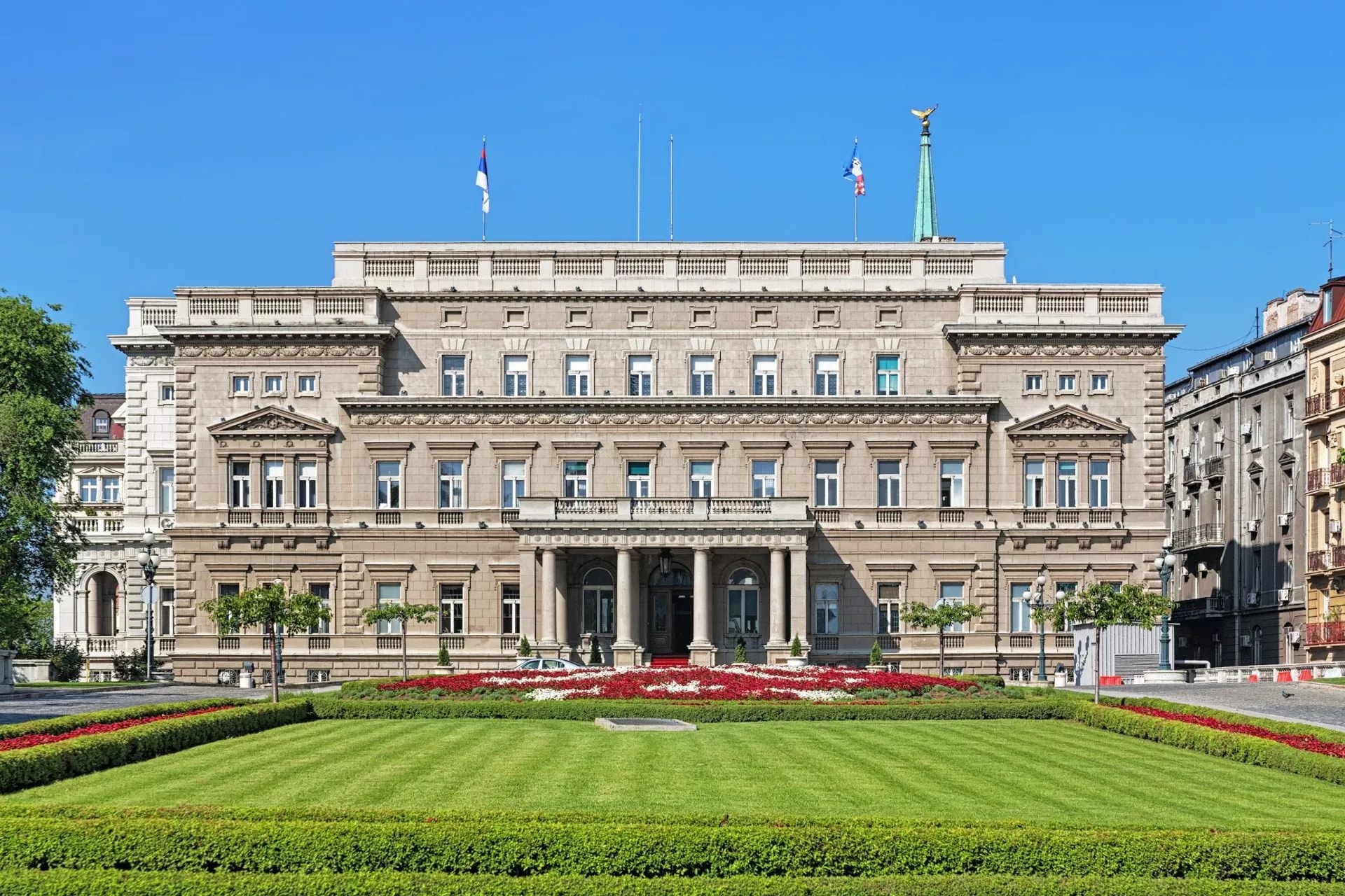 Stari Dvor Old Palace in Belgrade, Serbia, with manicured lawn and red flower beds.
