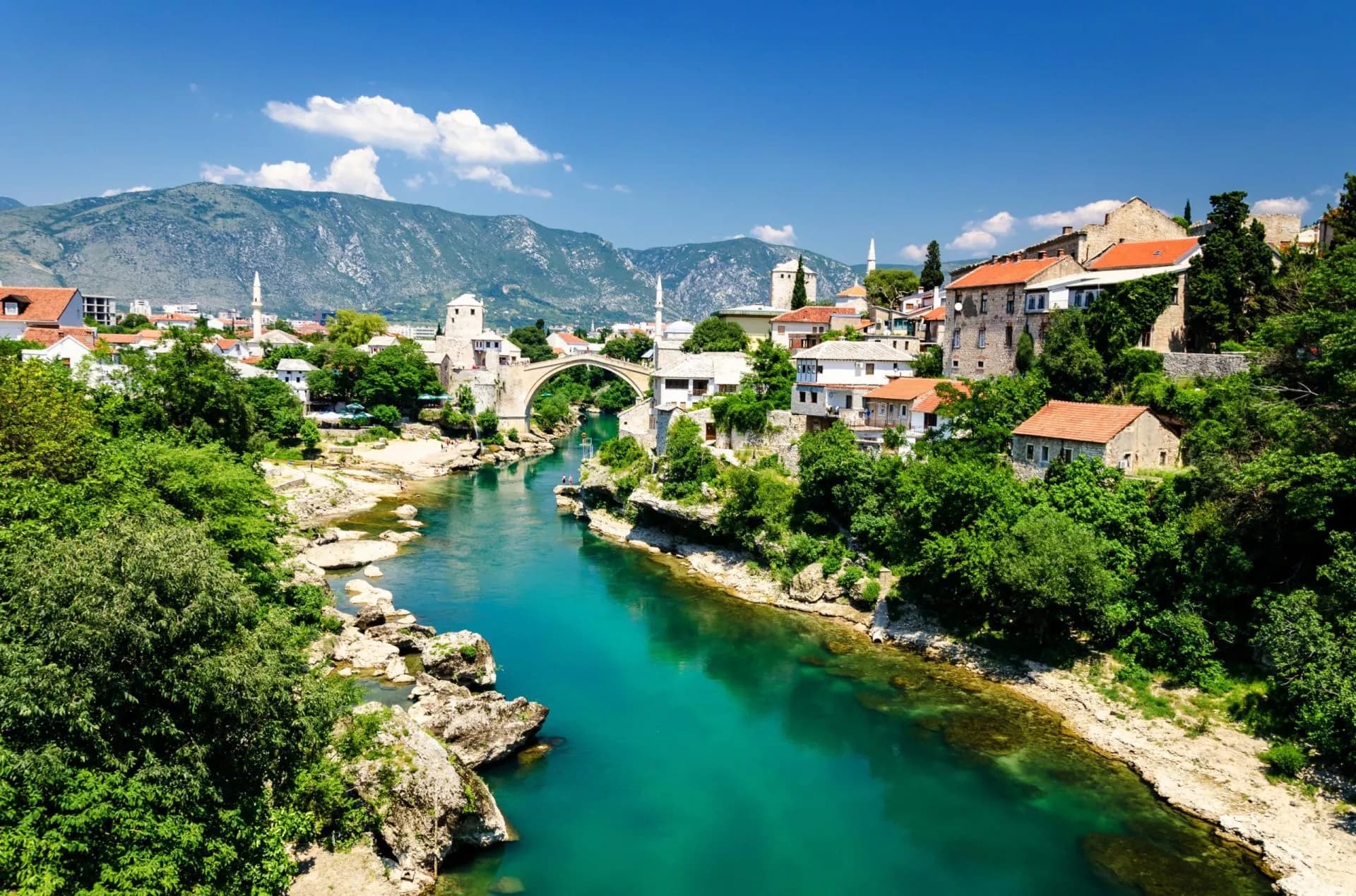 Old Bridge over emerald Neretva River in Mostar, Bosnia and Herzegovina, with mountains.