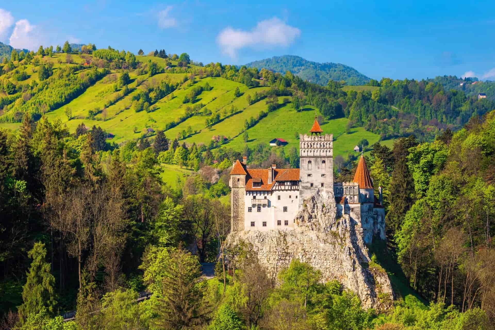 Spectacular Dracula Castle near Brasov, Bran, Transylvania, Romania, on a rocky outcrop with green hills.