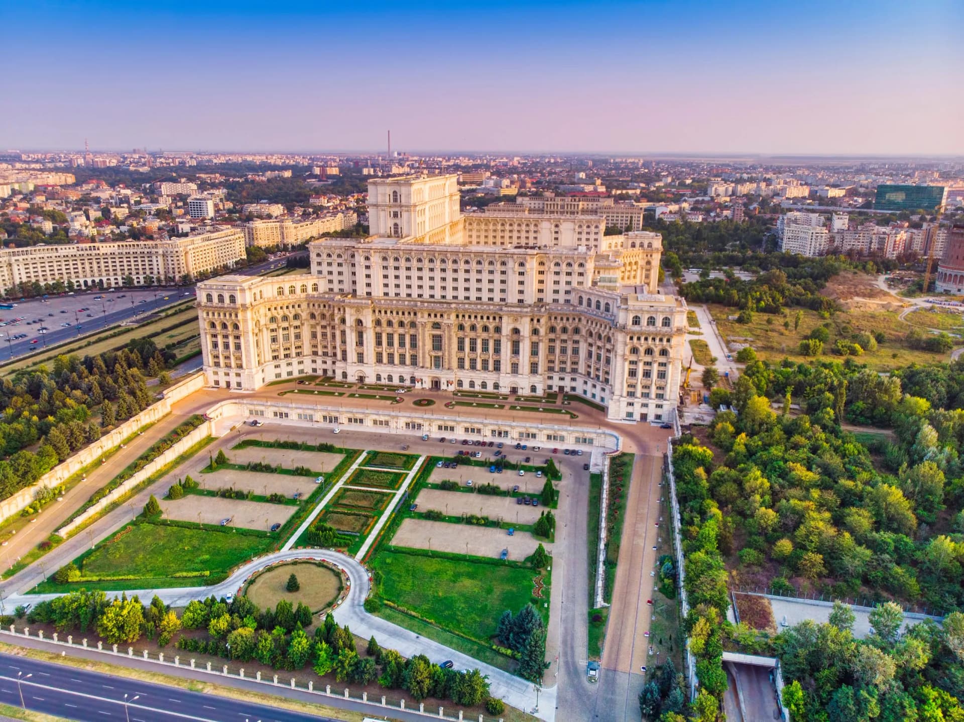 Aerial view of the Palace of the Parliament in Bucharest city at sunset with blue sky.