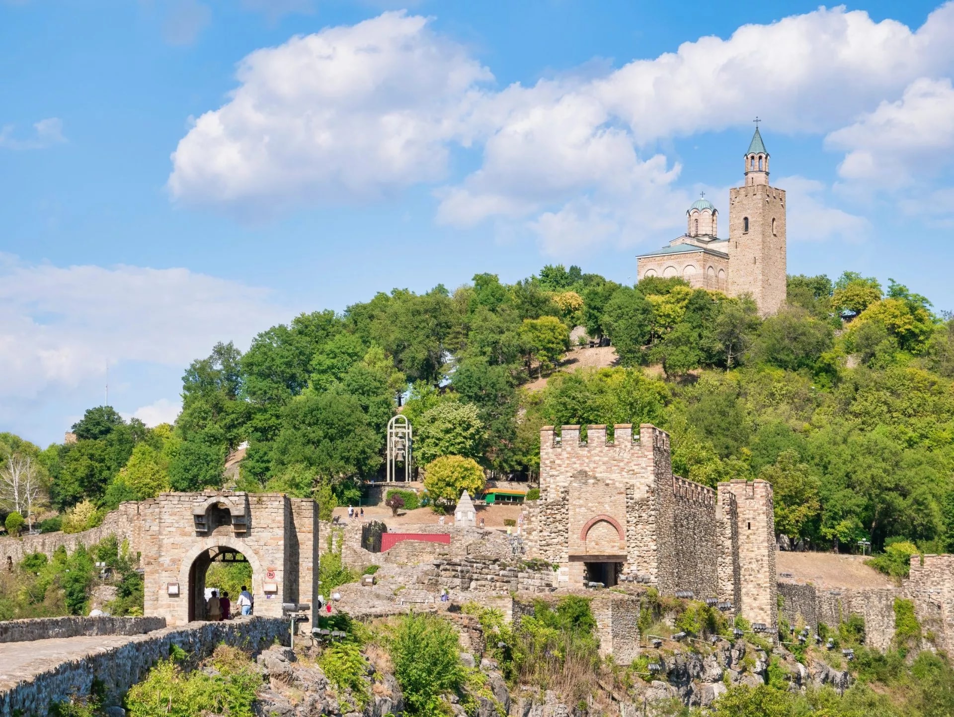 Ascension Cathedral in Tsarevets Fortress, Veliko Tarnovo, Bulgaria, with stone walls and green trees.
