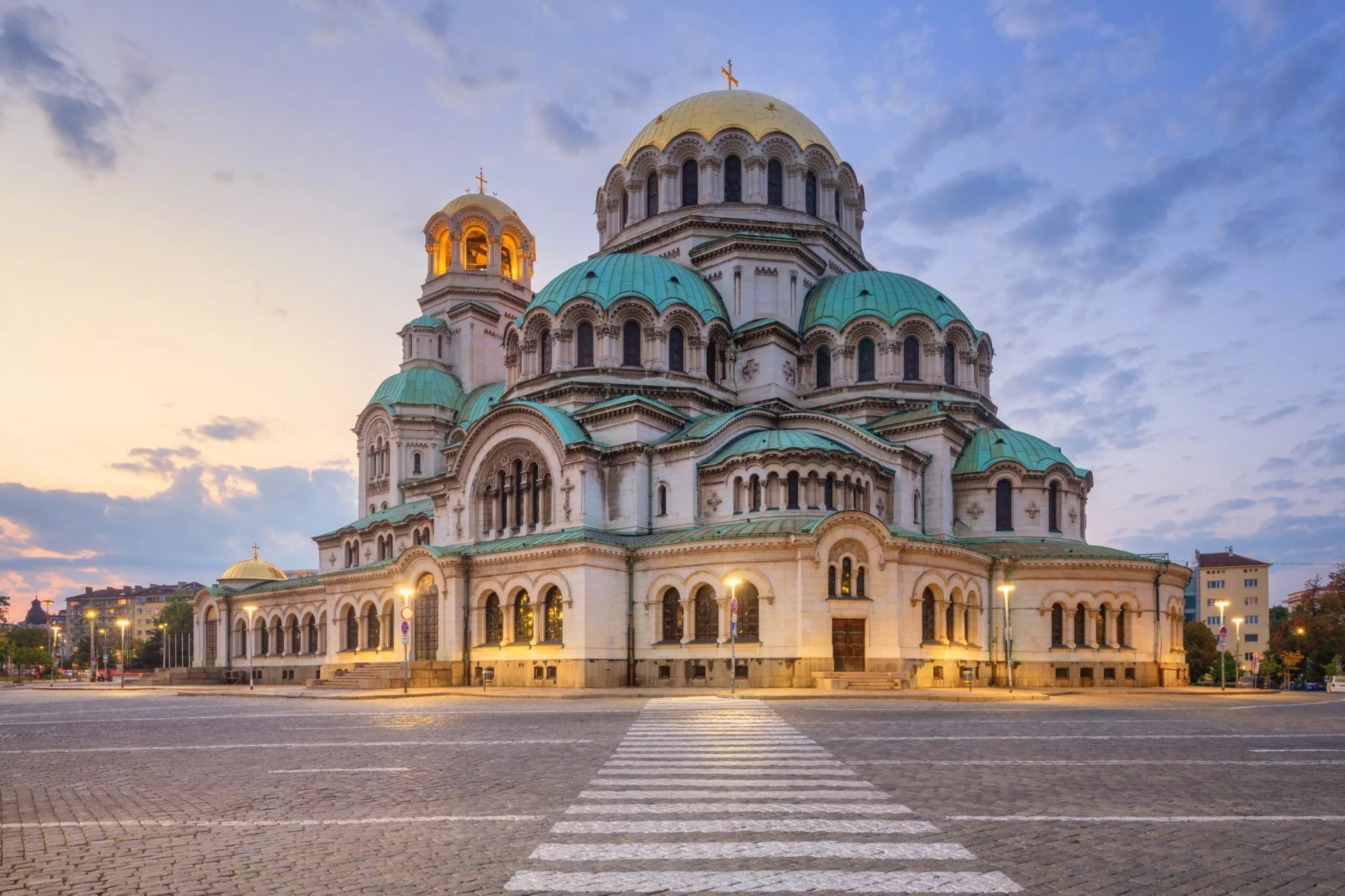Alexander Nevsky Cathedral in Sofia, Bulgaria, illuminated at sunset with gold and teal domes.